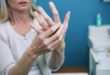 Frau massiert schmerzende Finger wegen Arthritis