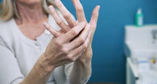 Frau massiert schmerzende Finger wegen Arthritis